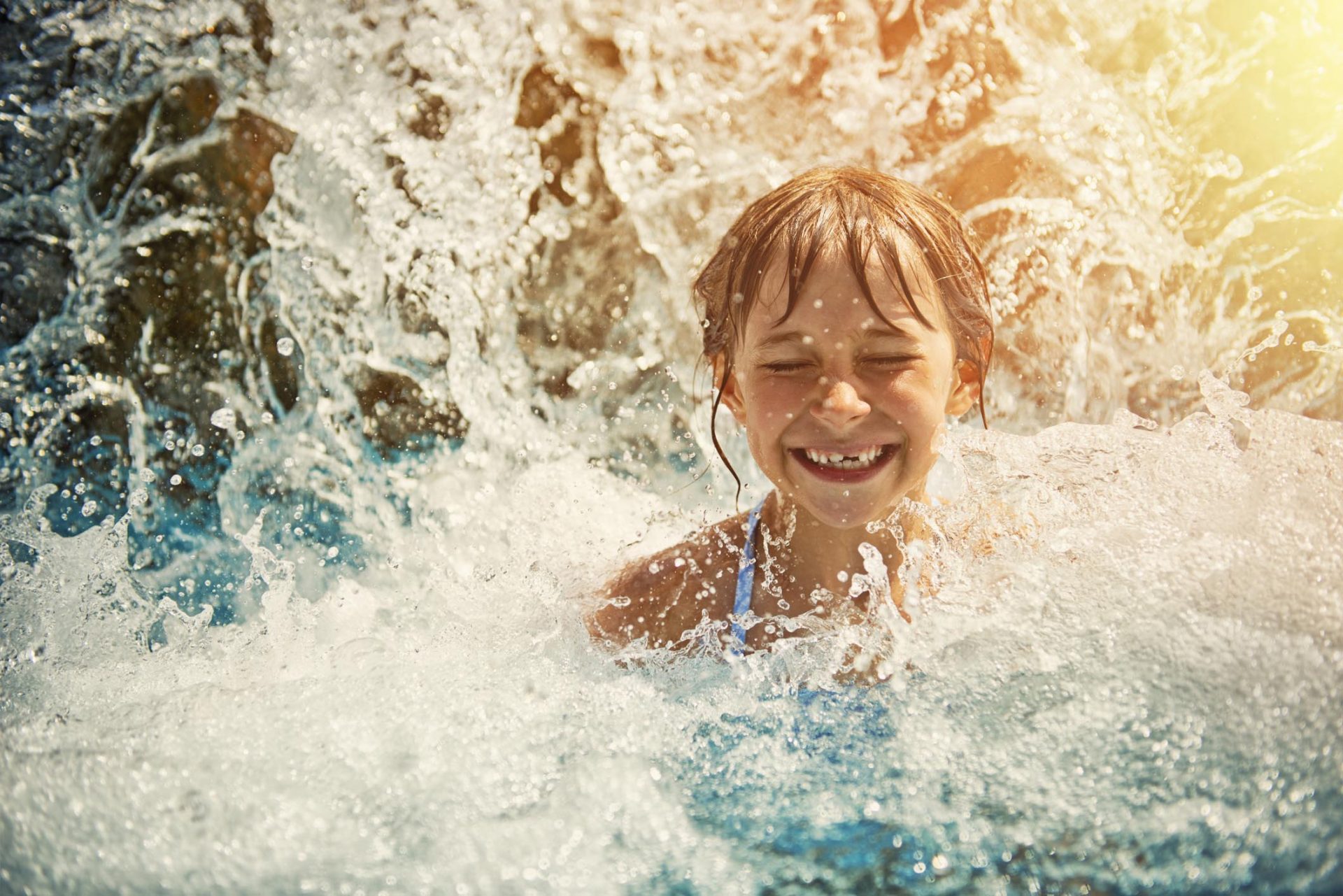 little-girl-playing-in-waterfall-in-waterpark-swimming-pool